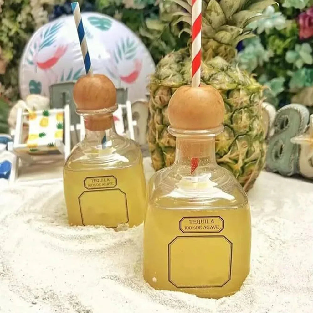 Two glass bottles of tequila are displayed on a white surface next to a pineapple.