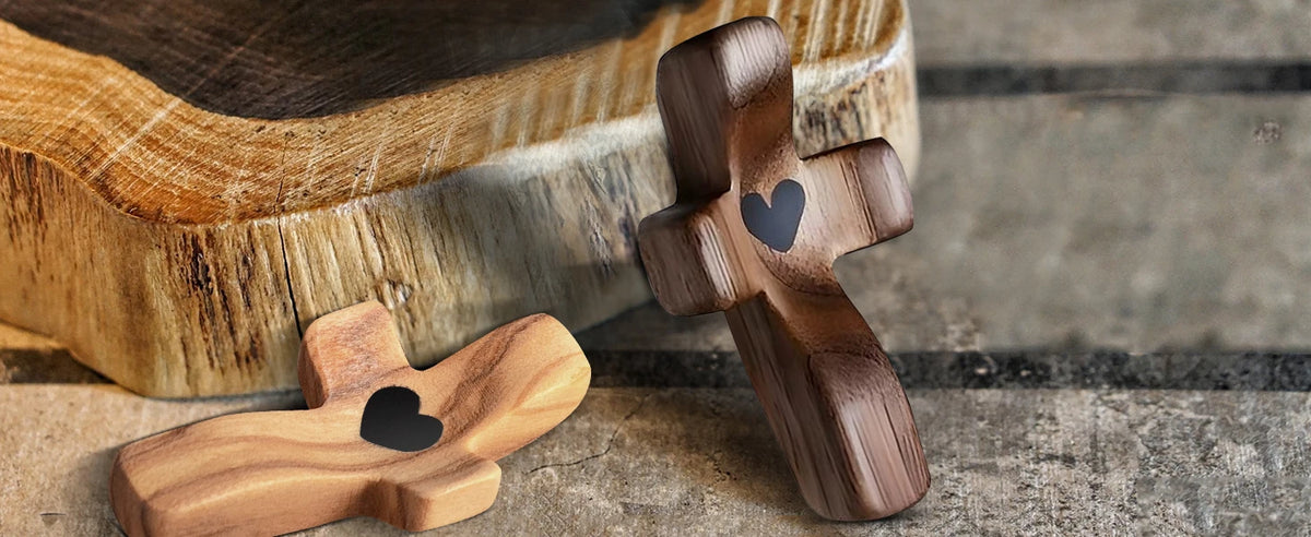 A wooden comfort prayer cross with a heart carved into it rests on a wooden tray.