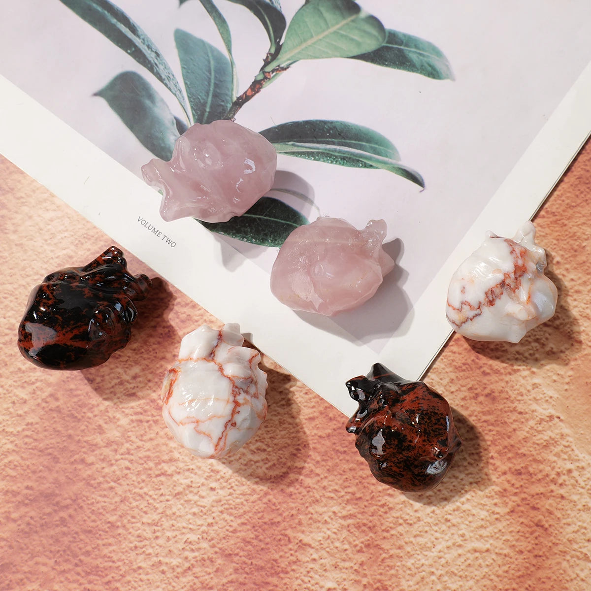 A collection of natural crystal heart carvings in pink and white hues displayed against a green leaf background.