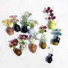 A collection of mini ceramic vases with artificial flowers in various colors and textures arranged on a white background.