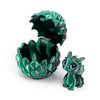 A dark green, textured dragon egg container is open, revealing a small, green dragon toy inside.