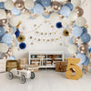 A wall decorated with a balloon arch and lettering spelling out Happy Birthday, featuring muted blue, gold, and white balloon