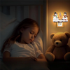 A young girl is sleeping in bed next to a teddy bear and a night light decoration shaped like a campfire.