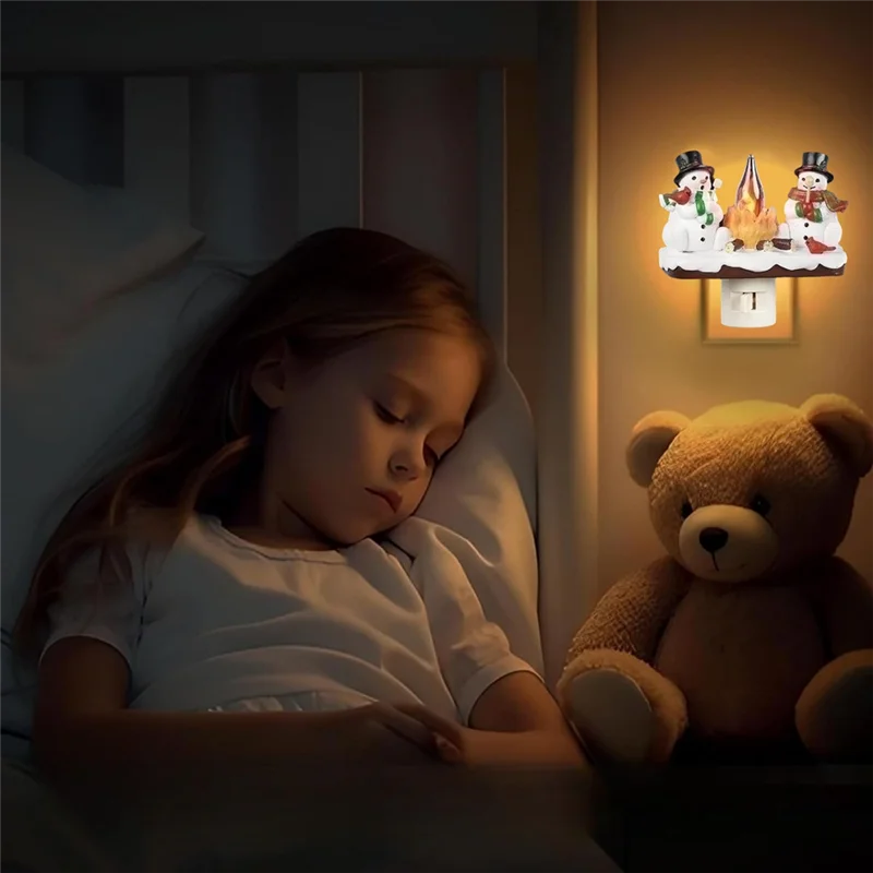 A young girl is sleeping in bed next to a teddy bear and a night light decoration shaped like a campfire.