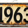 Señal de pared de aluminio vintage con el año 1963 grabado en una superficie oxidada y desgastada.