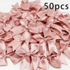 A pile of 50 pink satin ribbon bows for gift wrapping and decor.