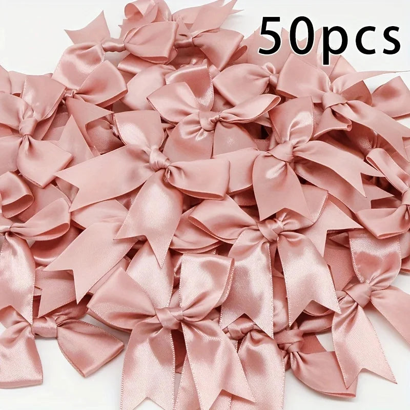 A pile of 50 pink satin ribbon bows for gift wrapping and decor.