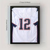 A framed white sports jersey with the number 12 and navy blue trim, displayed against a light background.