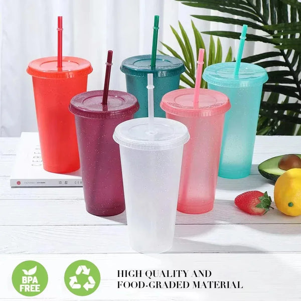 A collection of colorful glitter party cups with lids and straws displayed on a white surface.