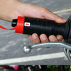 A hand is fitting a black silicone handlebar grip cover onto a motorcycle handlebar.