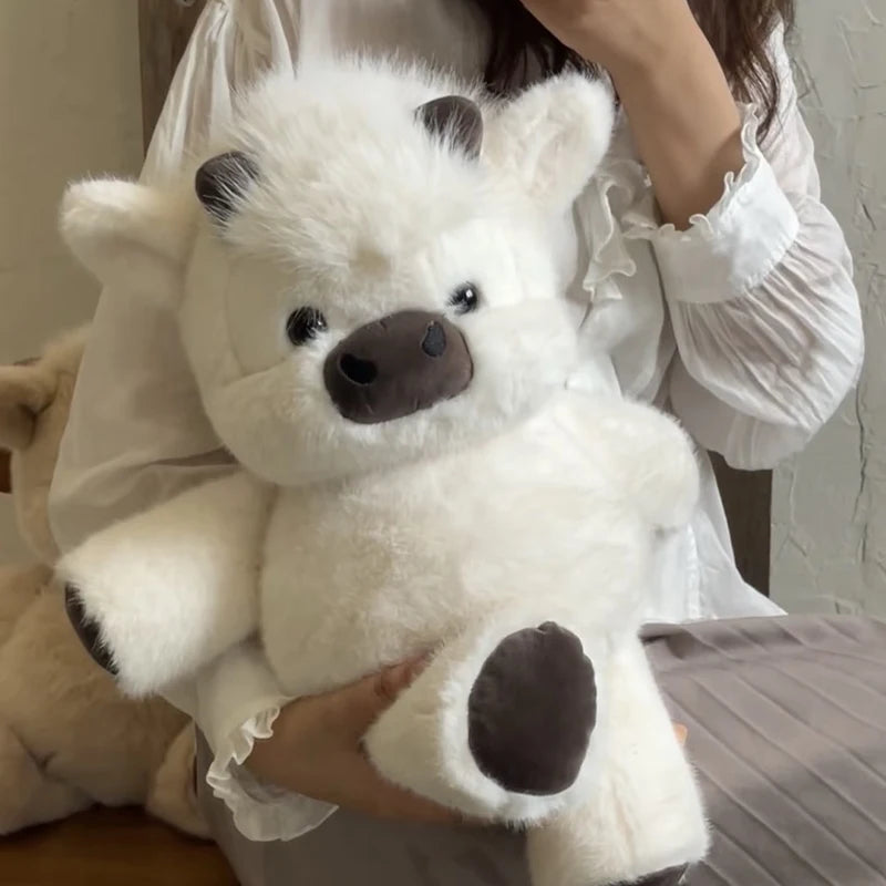Une personne tient une peluche de veau écossais Kawaii blanche.