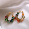 Gold-toned resin beaded drop earrings featuring various shades of green and amber stones.
