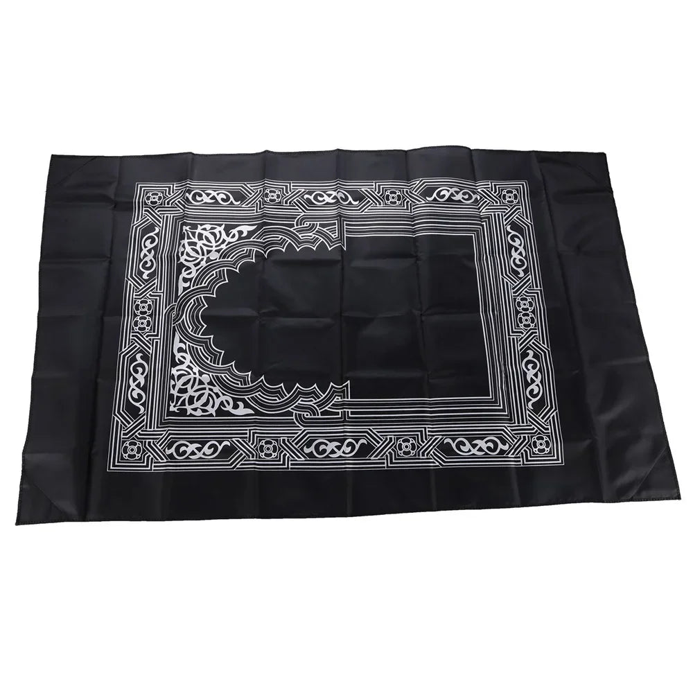 Black prayer mat with an ornate geometric border and a compass design.