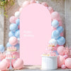 A pink and blue balloon arch backdrop featuring a large pink oval cutout and cupcakes.
