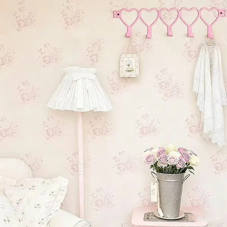 Pink heart over-the-door hook rack with five pink hooks mounted on a wall.