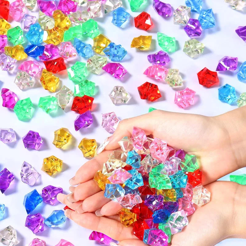 A hand holds a pile of colorful decorative crushed diamond acrylic pebbles.