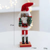 A handcrafted wooden nutcracker soldier figurine wearing a red Santa hat and green uniform, standing on a red base.