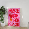 Pink canvas wall art featuring the text MORE AMOR POR FAVOR in bright red script on a white background