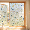 A close-up view of a window decorated with a delicate floral pattern and butterflies, showing light filtering through the gla