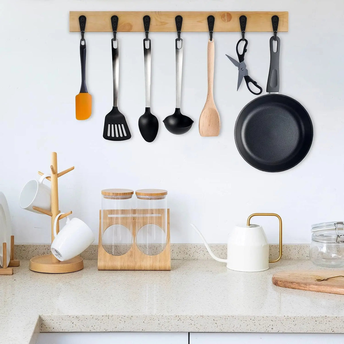 A collection of aluminum wall-mounted hooks with screws for coats, towels, and bags displayed on a white wall.