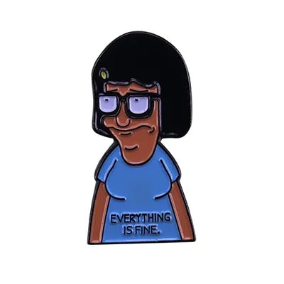 A enamel pin featuring a cartoon character with dark hair and glasses wearing a blue shirt.