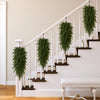A white staircase railing decorated with green artificial Christmas teardrop swag featuring Norfolk pine needles.