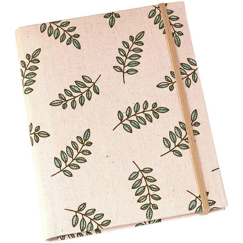 A beige linen photo album with a patterned cover featuring green leaves.