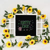 A white wooden frame decorated with yellow silk sunflowers and green vines for home decor.