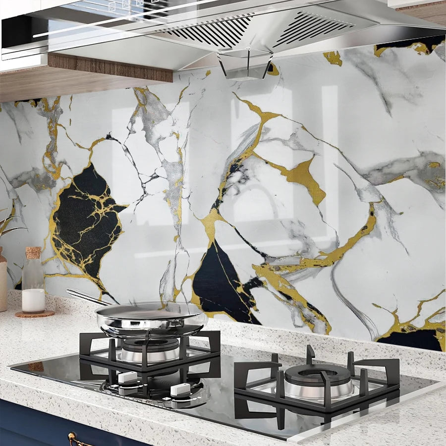 A kitchen backsplash featuring marble white and gold veining on a wall, with a modern stovetop below.