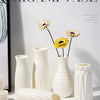 A collection of white plastic vases in various shapes and textures displayed against a light background.