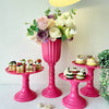 A pink table display featuring elegant gold cylinder flower vases and floral arrangements.
