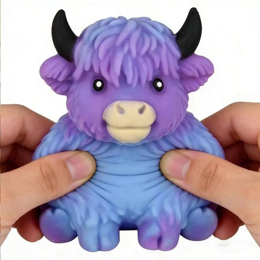 A purple and blue Scottish Highland cow squishy stress relief toy being held in a person's hands.