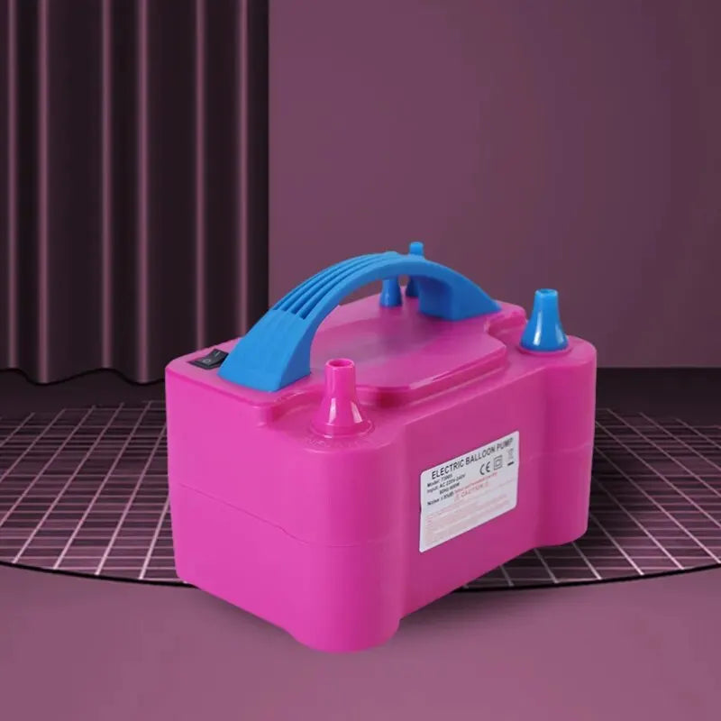 A pink electric balloon pump with a blue nozzle is shown on a dark surface.