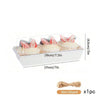 Clear plastic box containing three pink meringue pastries with green leaves and a twine bow