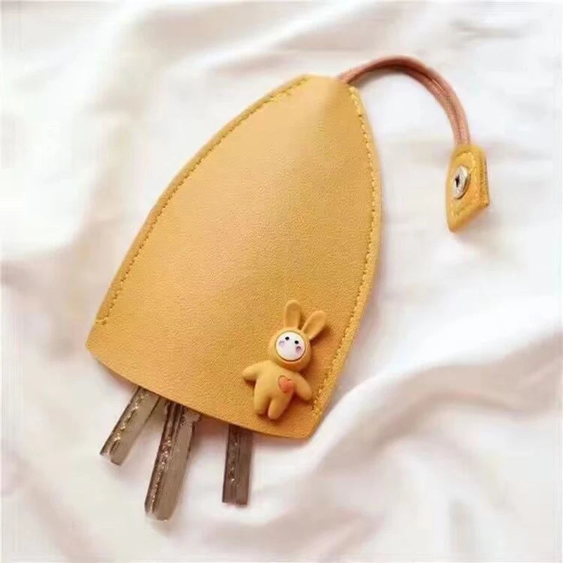 A tan cartoon PU leather key holder with a pull-out design attached to a brown leather cord.