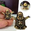 A brass laughing Buddha statue is held in a hand, showing its detailed features and golden color.