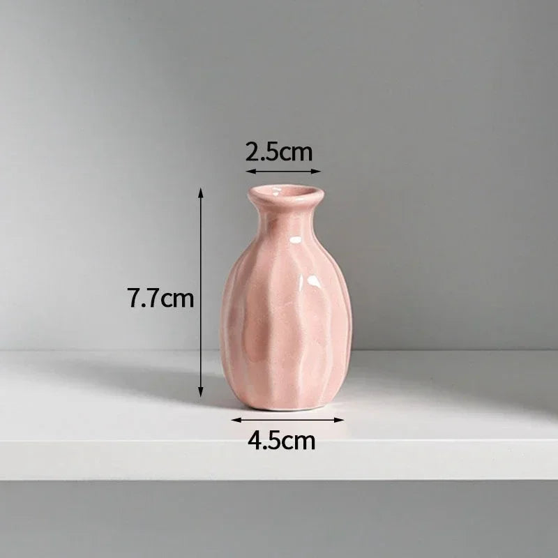 A pink ceramic mini vase with a rounded body and narrow neck, shown against a light gray background.