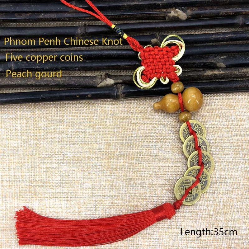 Red silk tassel featuring an antique copper five emperor coin pendant tied with a Chinese knot on beige fabric.
