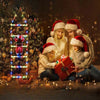 Four children in festive sweaters and Santa hats are gathered around a glowing Christmas tree decorated with LED lights.