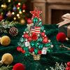 A sparkling green rhinestone Christmas tree brooch pin with a red star topper displayed on dark green velvet fabric.