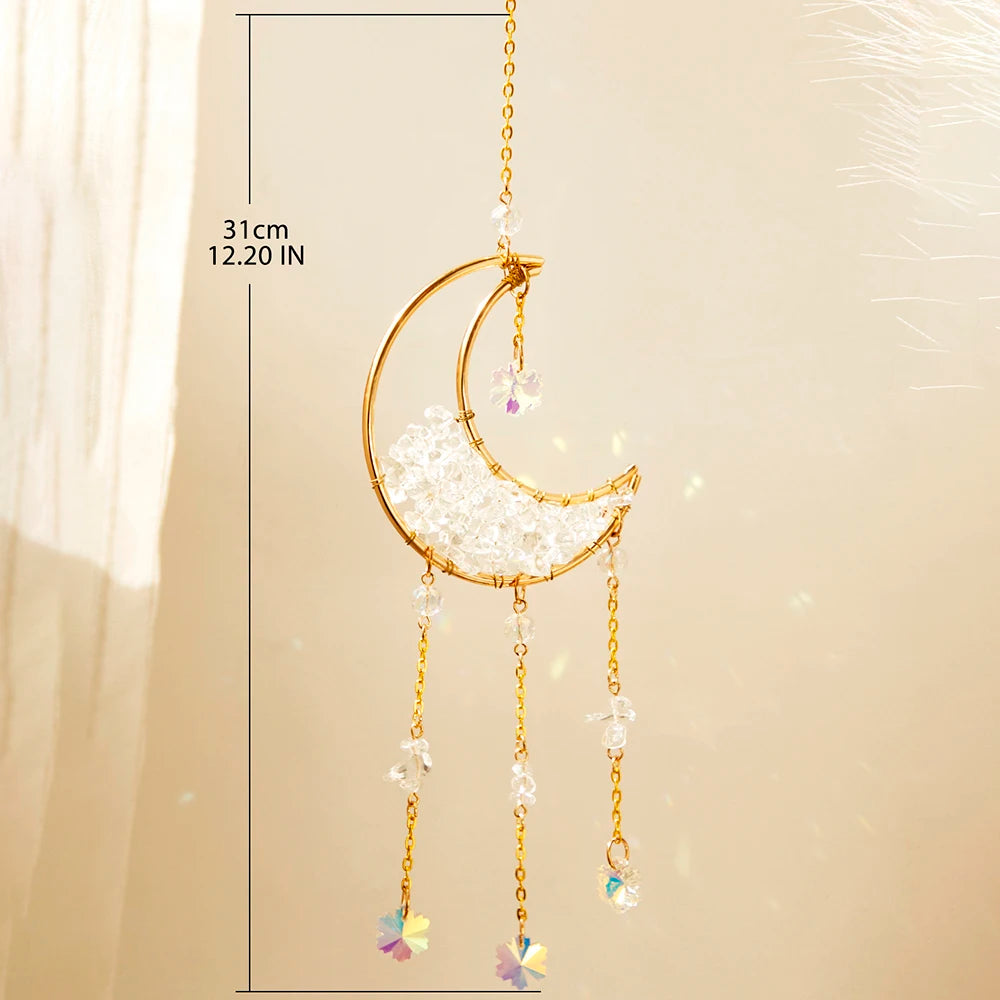 A gold moon-shaped crystal suncatcher with dangling rainbow prisms suspended by a chain.