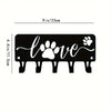 Black decorative metal wall-mounted key holder with seven hooks shaped like paw prints and a heart.