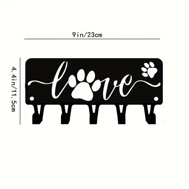 Black decorative metal wall-mounted key holder with seven hooks shaped like paw prints and a heart.