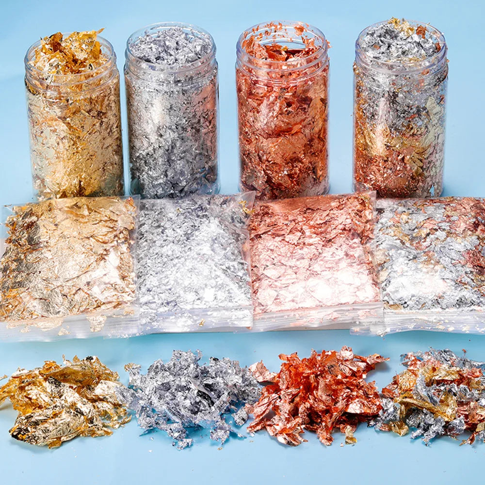 Various colors of shiny gold foil flakes for resin art and jewelry making displayed in glass jars and plastic bags.