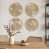 A set of four round wooden wall art pieces with concentric circle patterns displayed on a white wall above a wooden table.