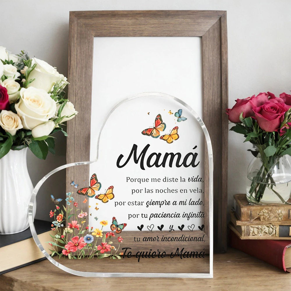 A framed piece of art featuring a heart shape and text dedicated to Mom, surrounded by floral elements.
