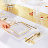 A close-up of a gold plastic dinnerware set laid out on a white tablecloth with gold glitter runner and glassware.