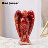 A polished red jasper figurine shaped like a guardian angel, resting on a light surface.