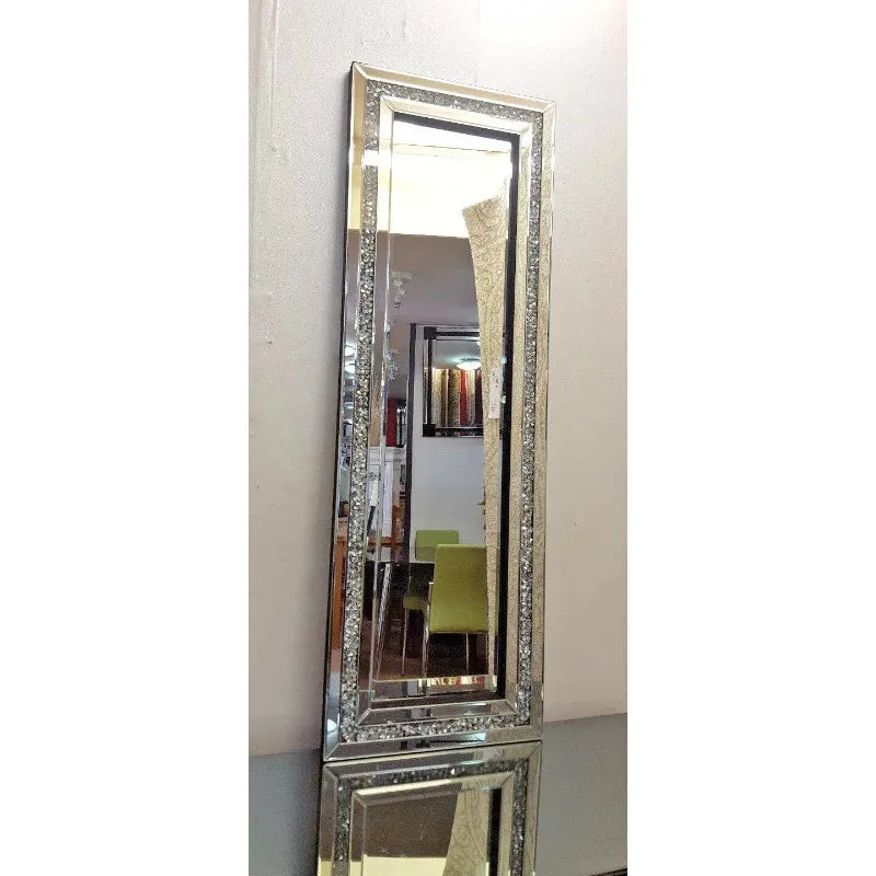A tall silver crystal beveled wall mirror reflecting an interior room.