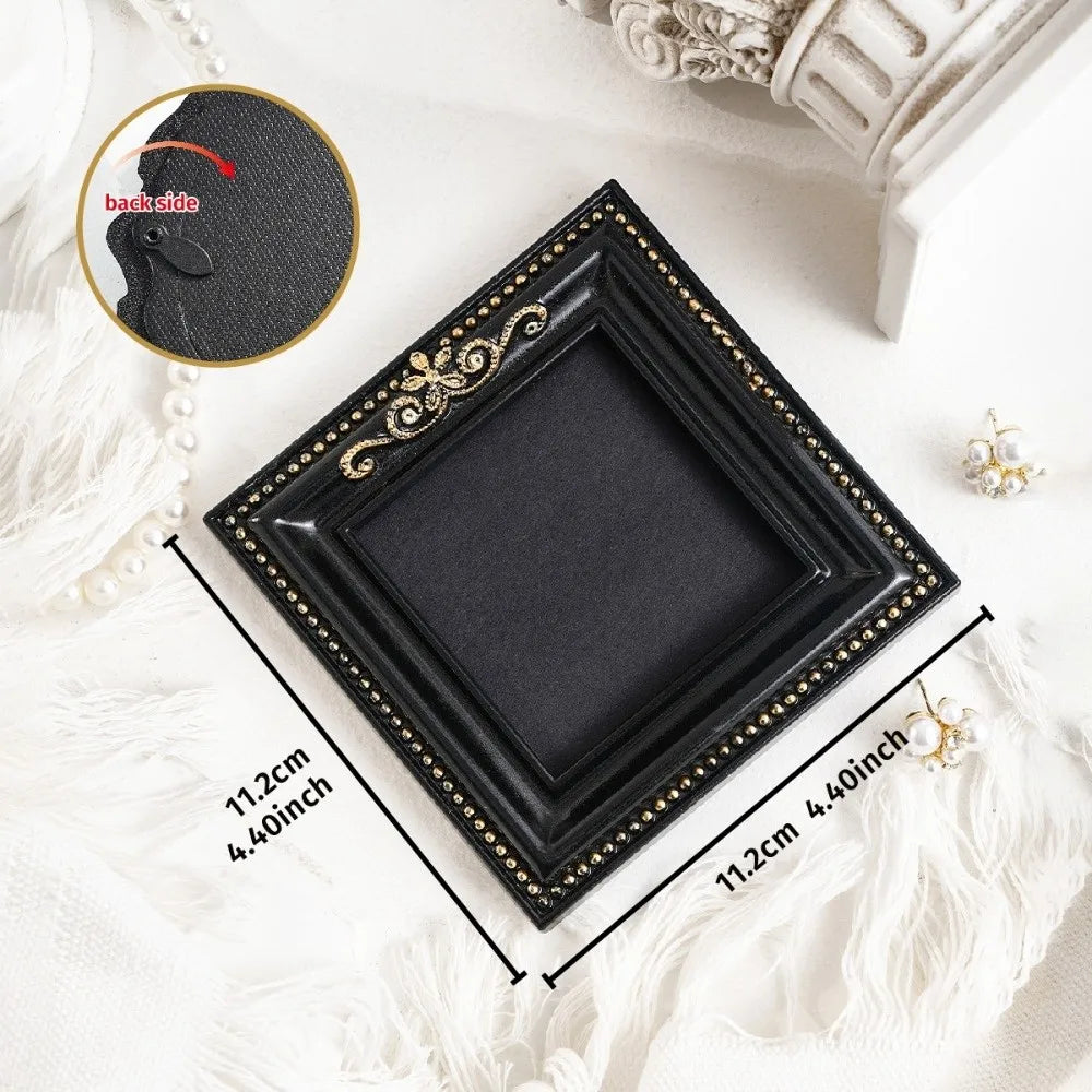 Black vintage baroque resin hanging photo frame with gold accents displayed on white fabric.